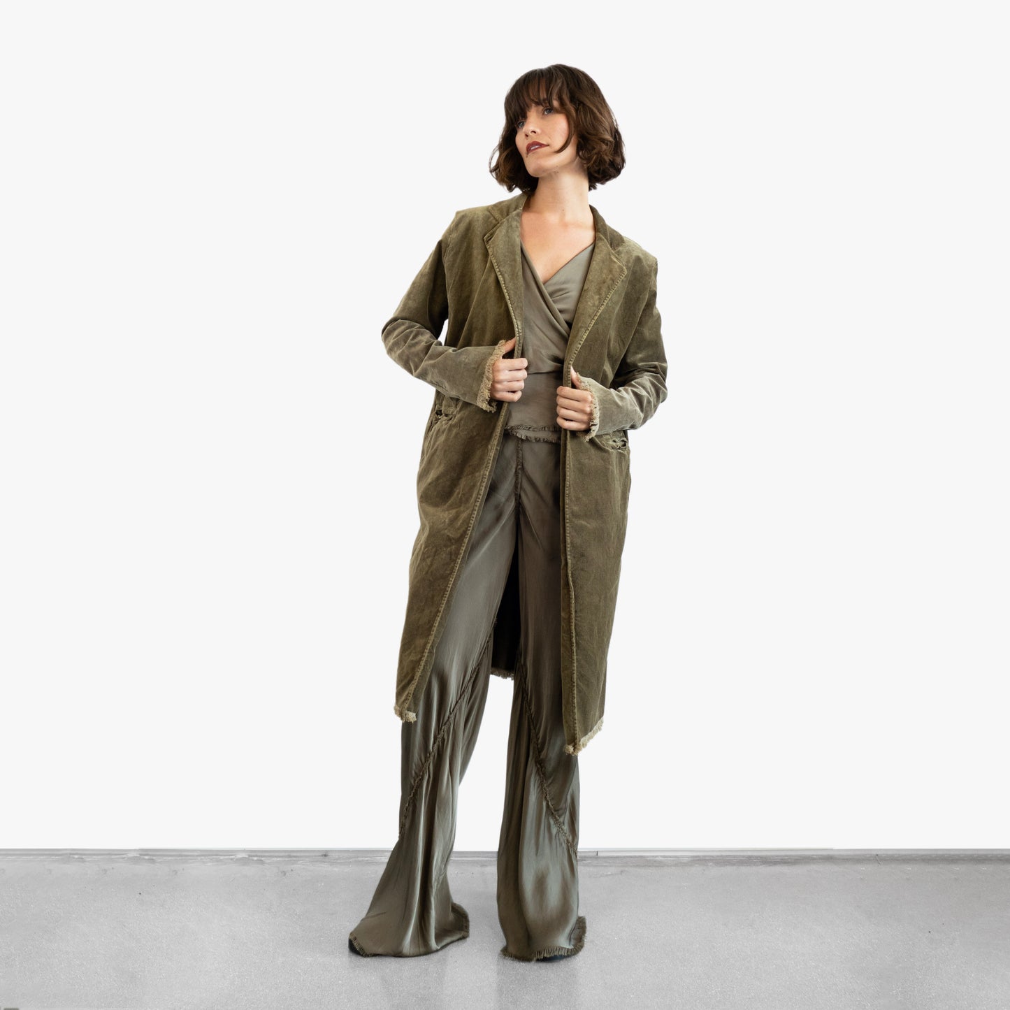 Model wearing a green velvet coat over a green silk wrap top and pants