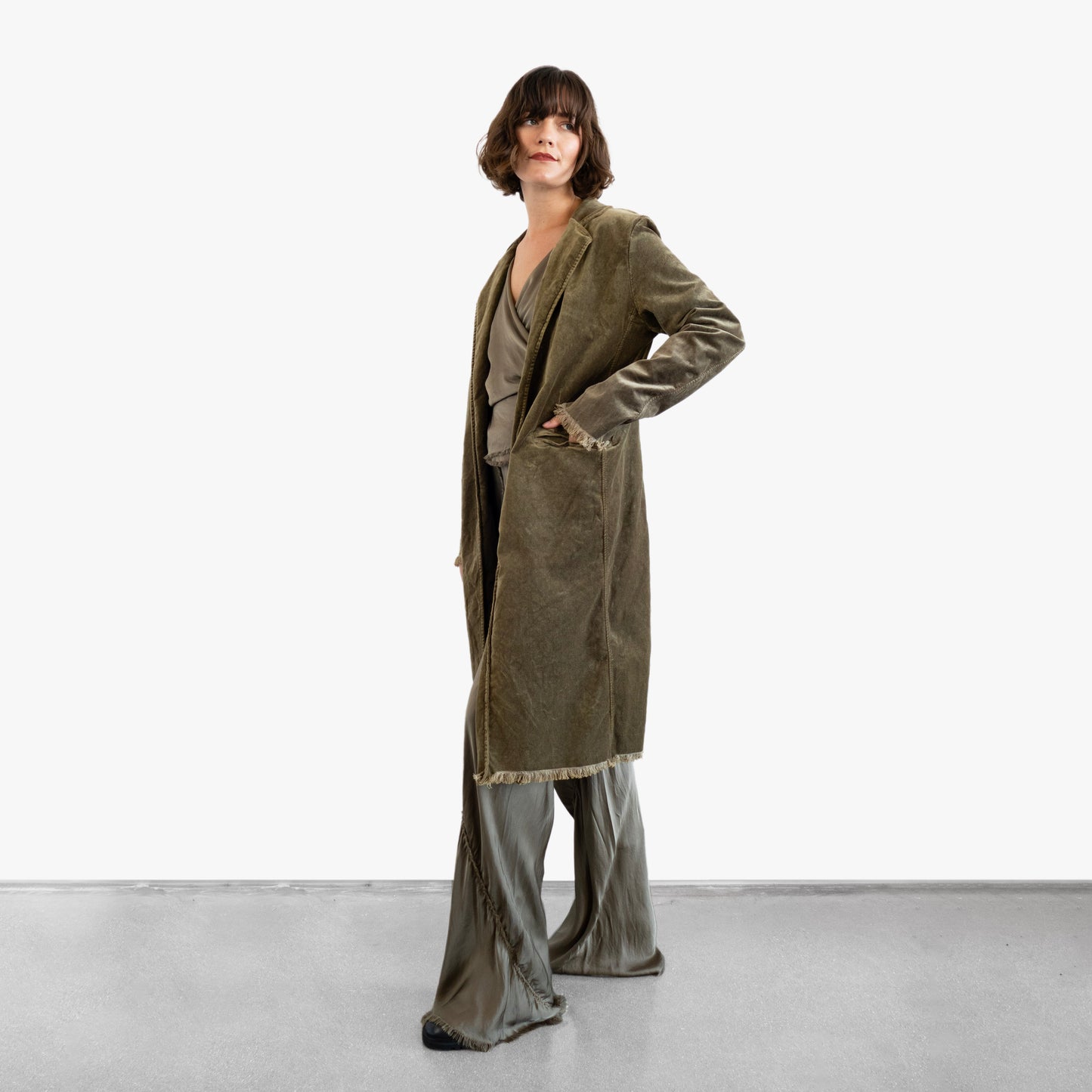 Model wearing a green velvet coat over a green silk wrap top and pants