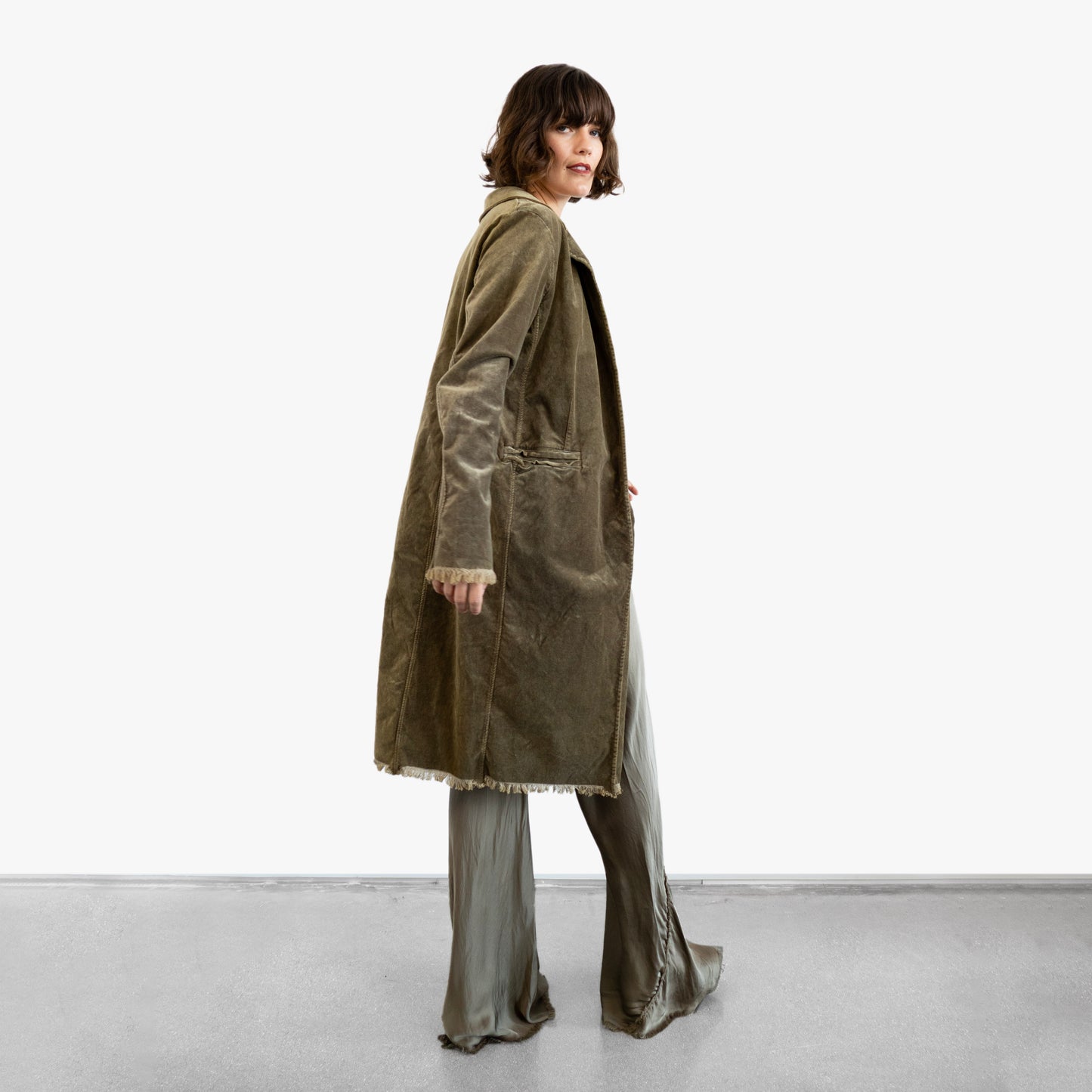 Model wearing a green velvet coat over a silk wrap top and silk pants