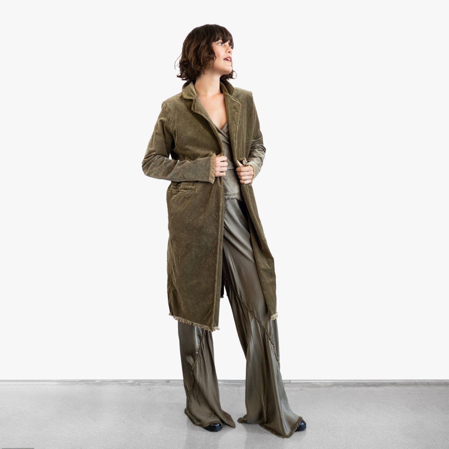 Model wearing a green velvet coat over a green silk wrap top and pants