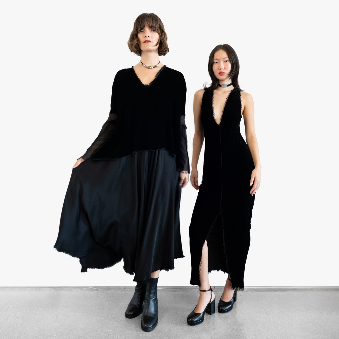 Model wearing a black velvet blouse and black silk skirt and another model wearing a black velvet dress