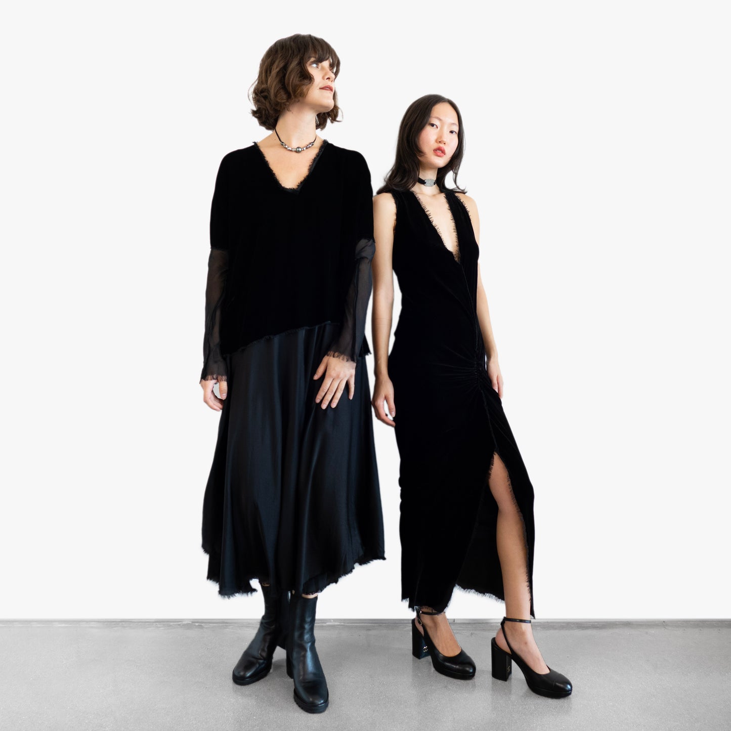 Model wearing a black velvet blouse and black silk skirt and another model wearing a black velvet dress
