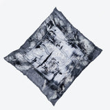 A limited edition hand-painted cashmere and silk scarf in gray, black, and white tones with frayed edges and a silver lamination.