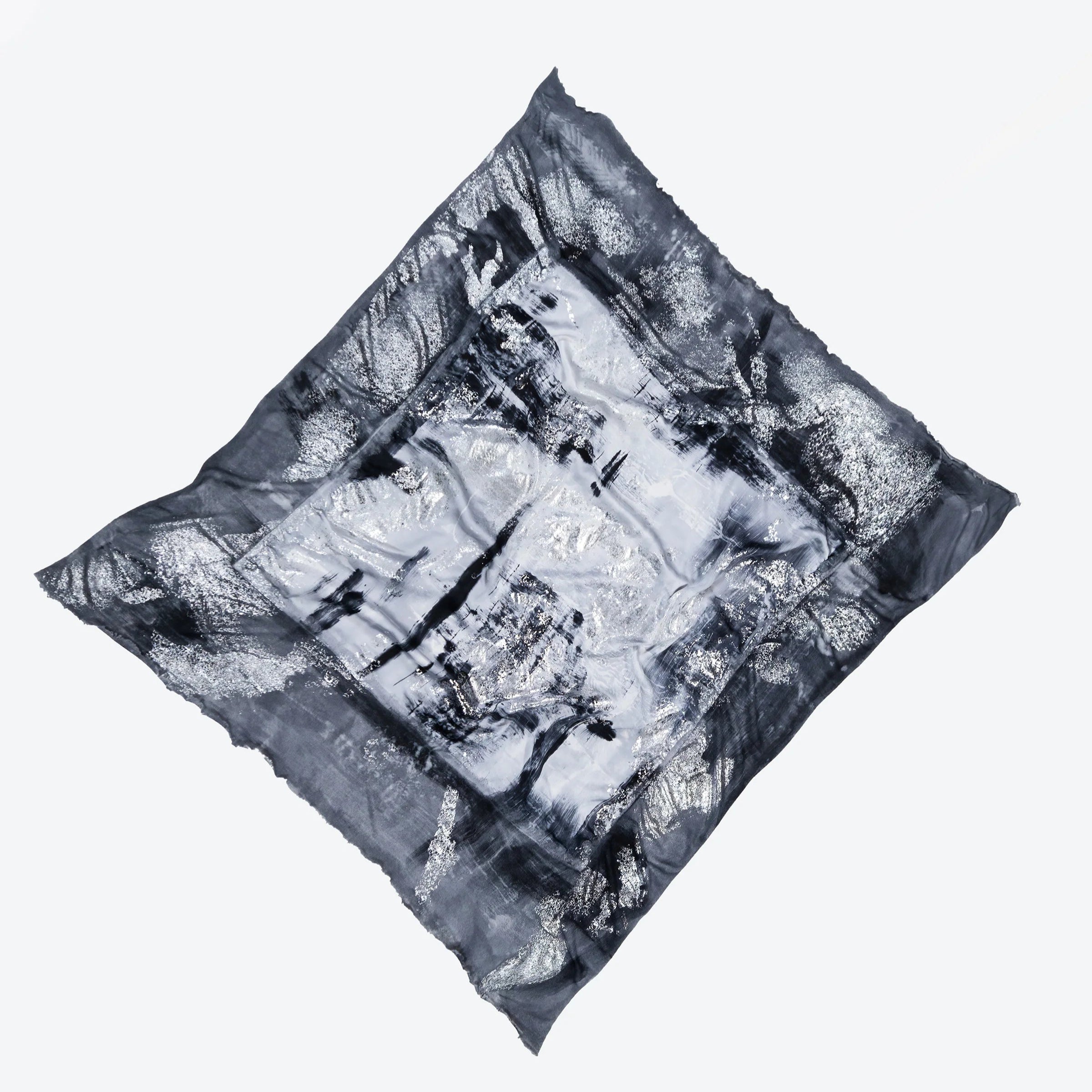 A limited edition hand-painted cashmere and silk scarf in gray, black, and white tones with frayed edges and a silver lamination.