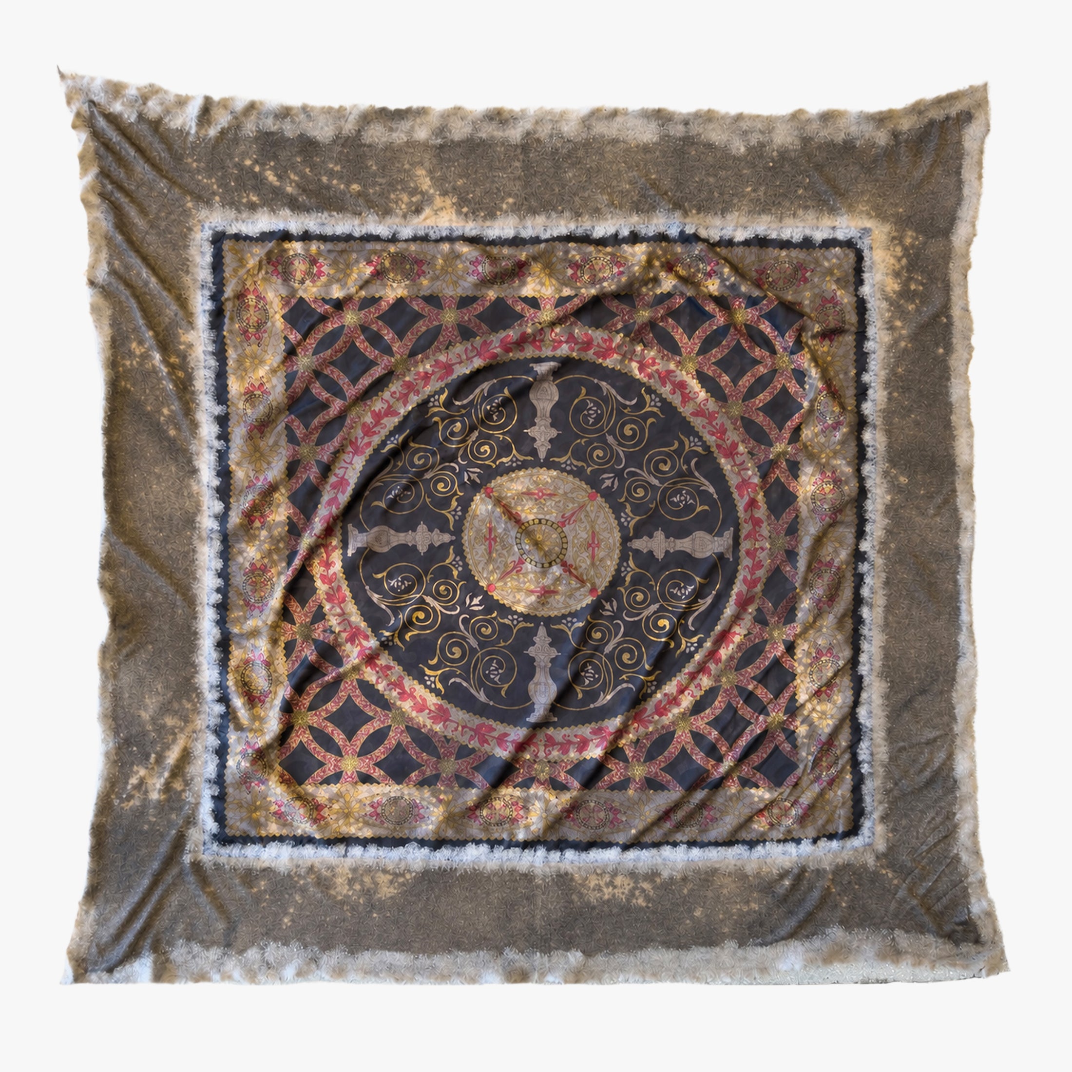 A square silk and cashmere scarf with a distressed, vintage-style design. The scarf features a central circular medallion in black, gold, and red, surrounded by a geometric lattice pattern, and finished with a frayed, distressed brown border.