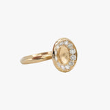 A 14K gold circular cocktail ring set with diamonds around it.