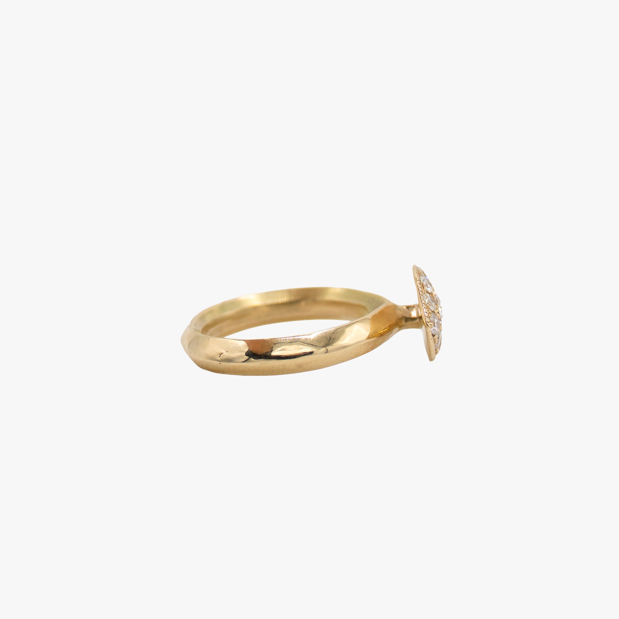 A gold eye-shaped ring with a pavé diamond halo and a central round diamond, shown on a light gray background.