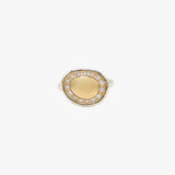 A two-tone oval ring featuring a smooth gold center surrounded by a halo of small clear stones, set in a silver-toned band.