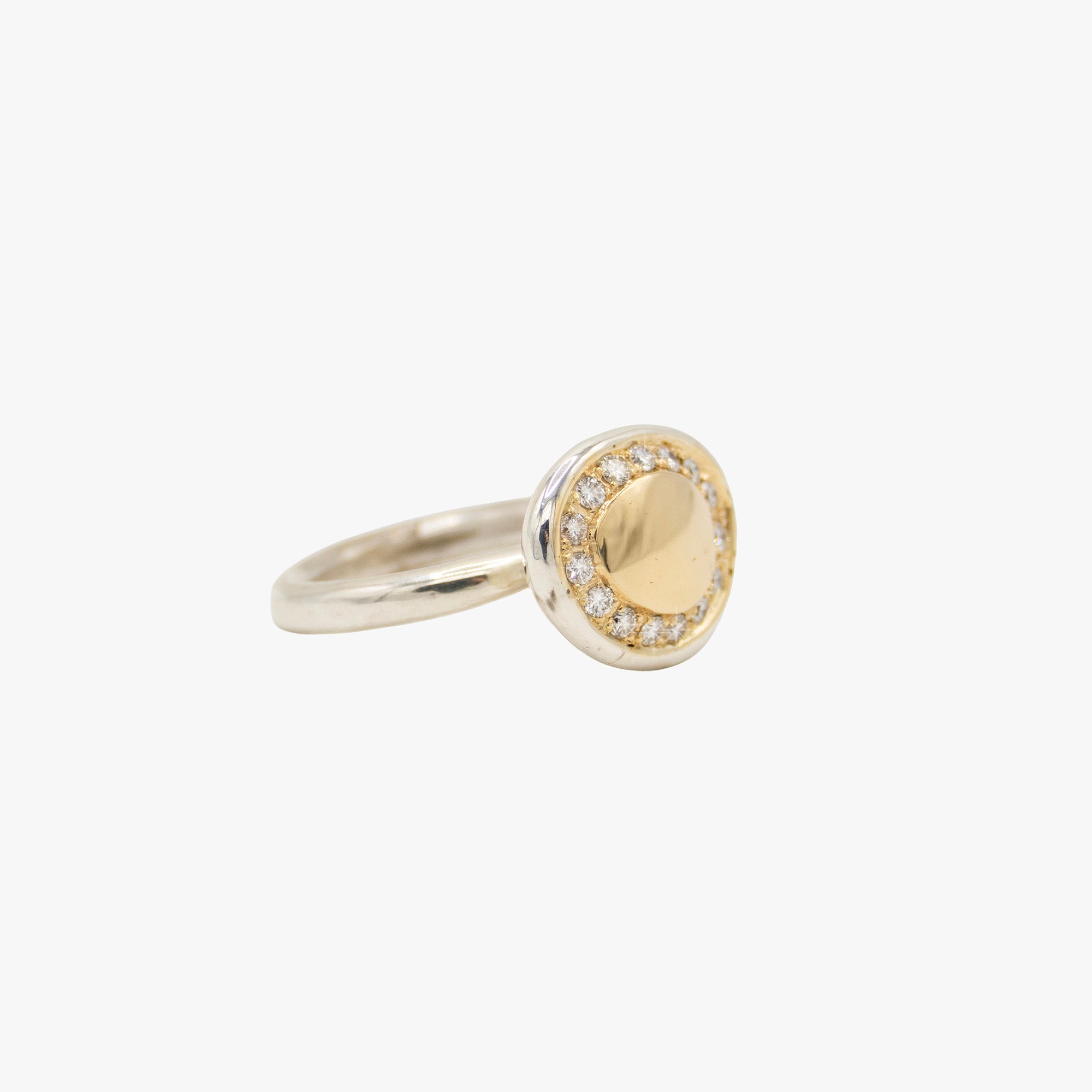 A two-tone oval ring featuring a smooth gold center surrounded by a halo of small clear stones, set in a silver-toned band.