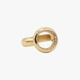 A gold ring featuring a circular openwork top set with small clear stones along the inner edge.