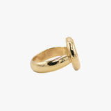A gold ring with a thick, polished band and a round face, shown from a side angle.