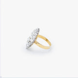 A yellow gold ring with a silver-toned oval pavé setting featuring clear round stones, shown on a light gray background.