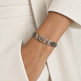 a woman wearing a sterling silver and diamond bracelet with her hands in her pocket