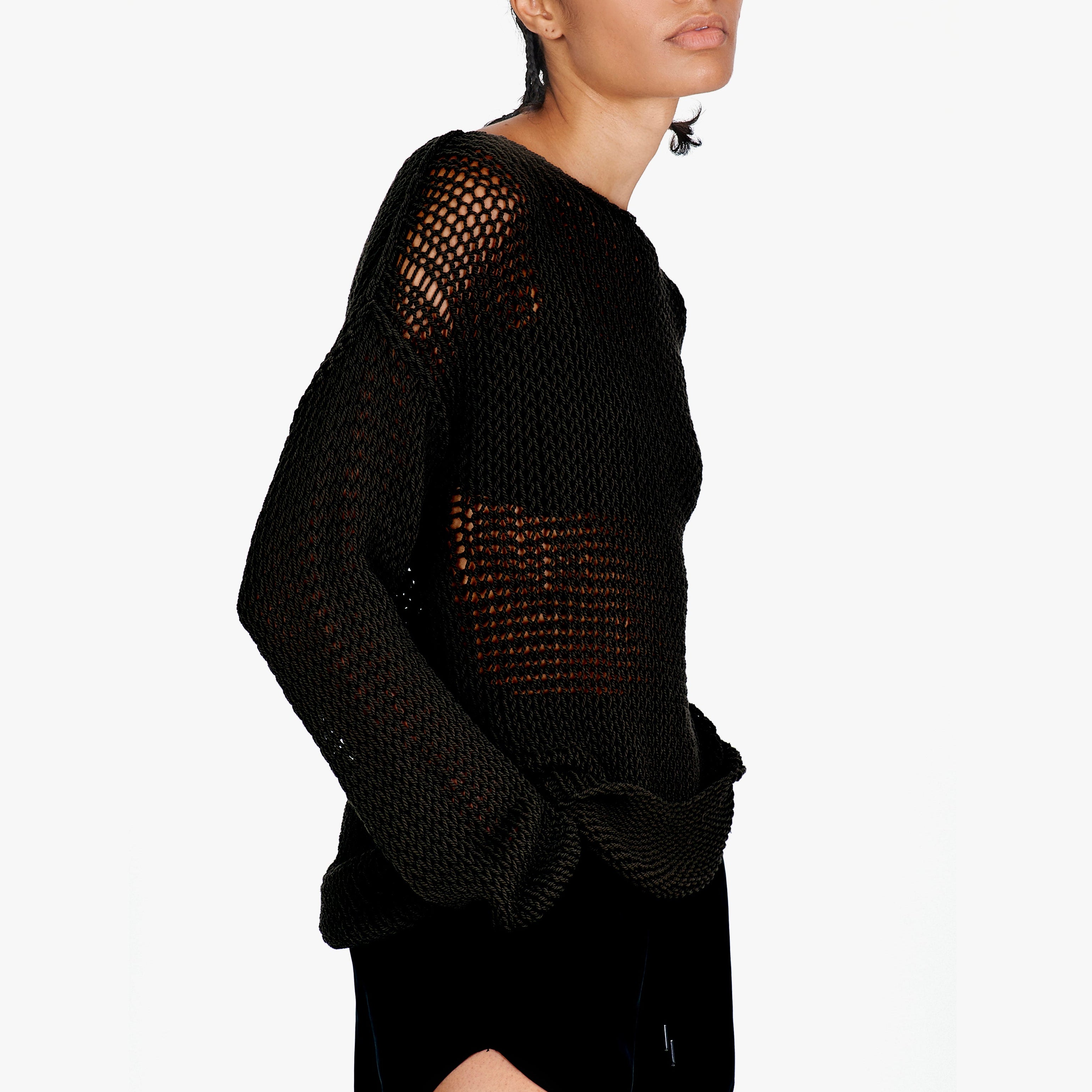 A model shown from the side wearing a black open-knit long-sleeve sweater against a plain white background.