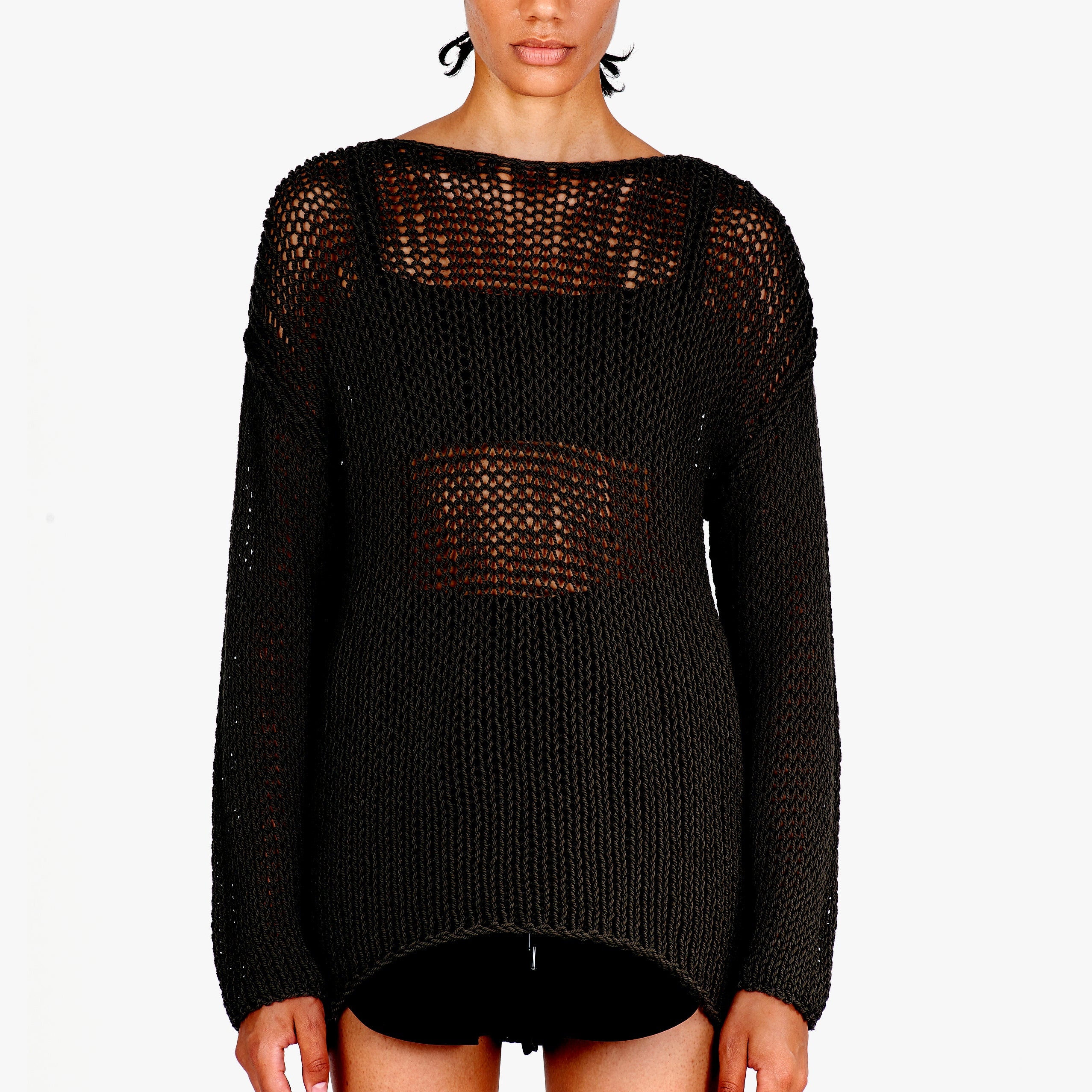 A woman wearing a black open-knit long-sleeve sweater with a boat neckline, photographed against a plain white studio background.
