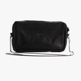 A black textured leather crossbody bag with a silver-tone chain strap and a small horizontal metal plaque on the front, shown against a plain light gray background.