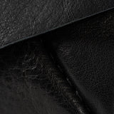 Close-up of black textured leather material with visible grain and stitched edges.