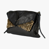 Black leather clutch bag with a gold metallic feather-like embellishment across the front flap, shown on a light gray background.