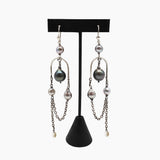 A pair of long silver-toned dangle earrings with Tahitian and South Sea pearls, displayed on a black T-stand against a light gray background.