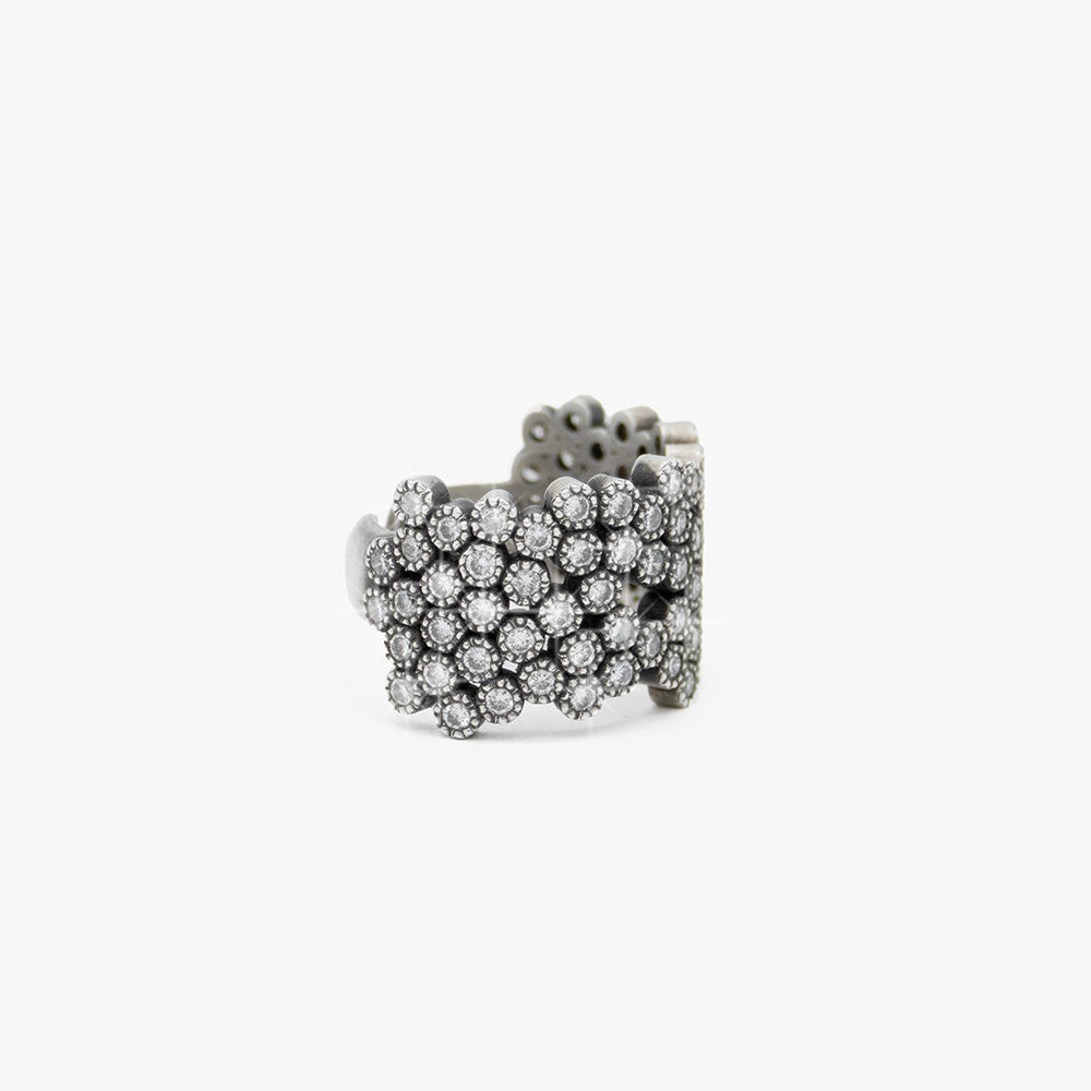 A wide silver cuff ring embellished with multiple rows of diamonds, photographed on a clean white background.