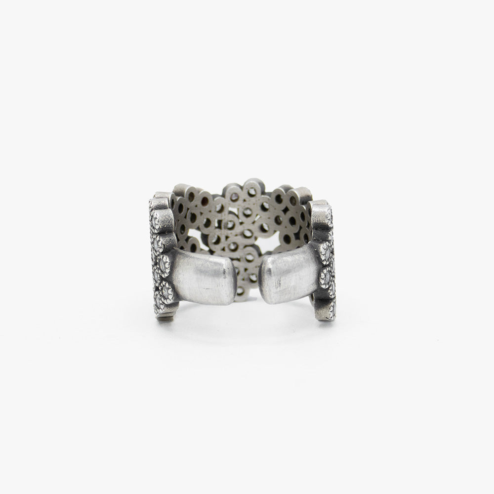 A wide silver cuff ring embellished with multiple rows of diamonds, photographed on a clean white background. 