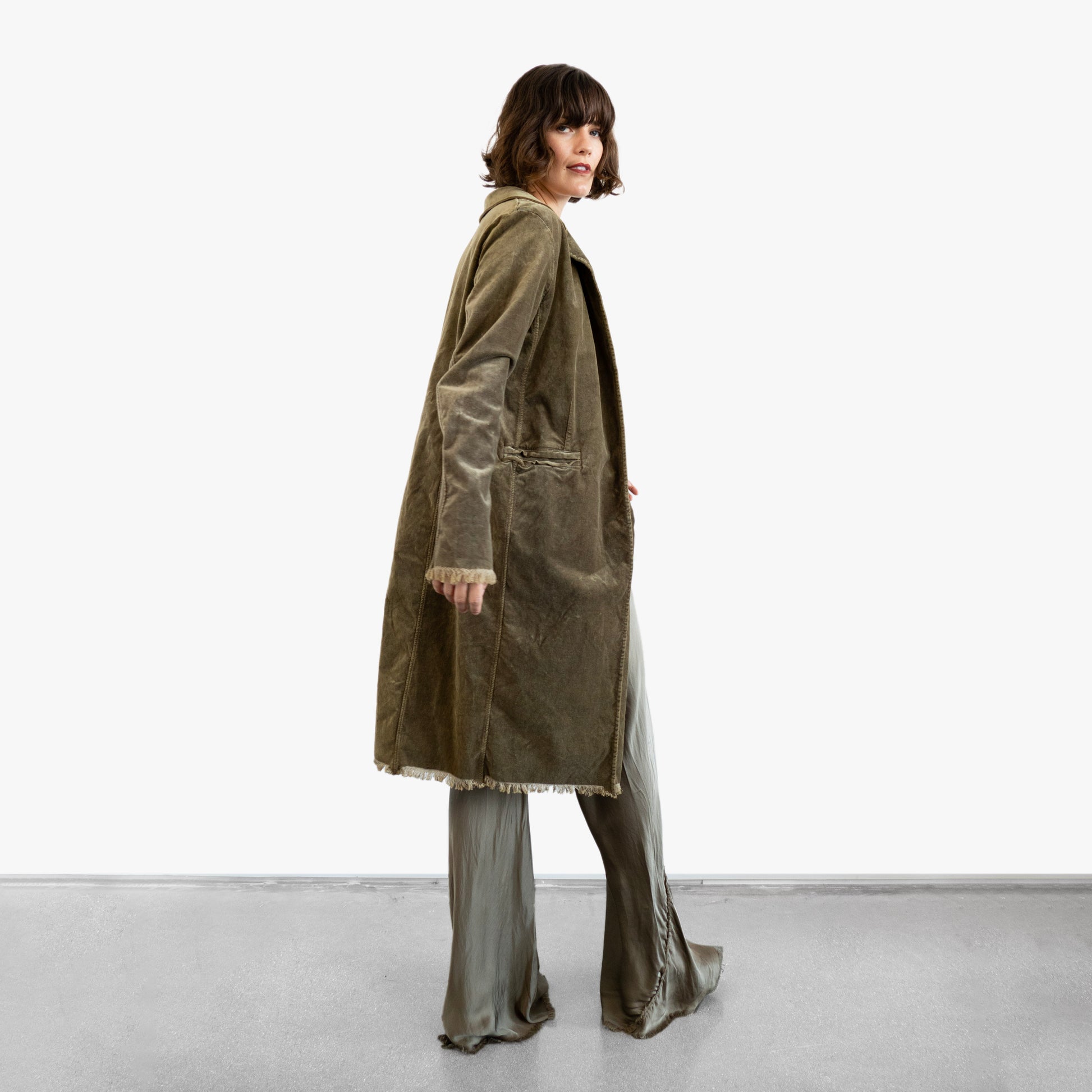 Model wearing a green velvet coat over a green silk wrap top and pants