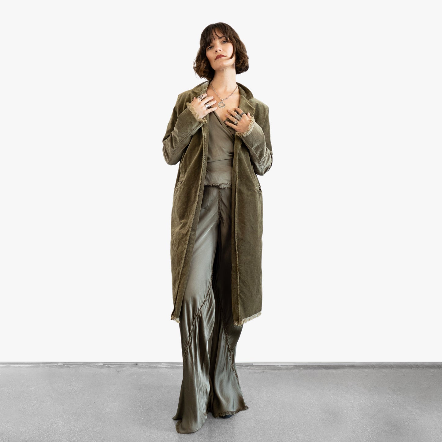 Model wearing a green velvet coat over a silk wrap top and silk pants