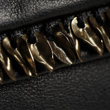 Close-up of a black textured leather item featuring a row of metallic gold bird-shaped hardware accents along the edge.