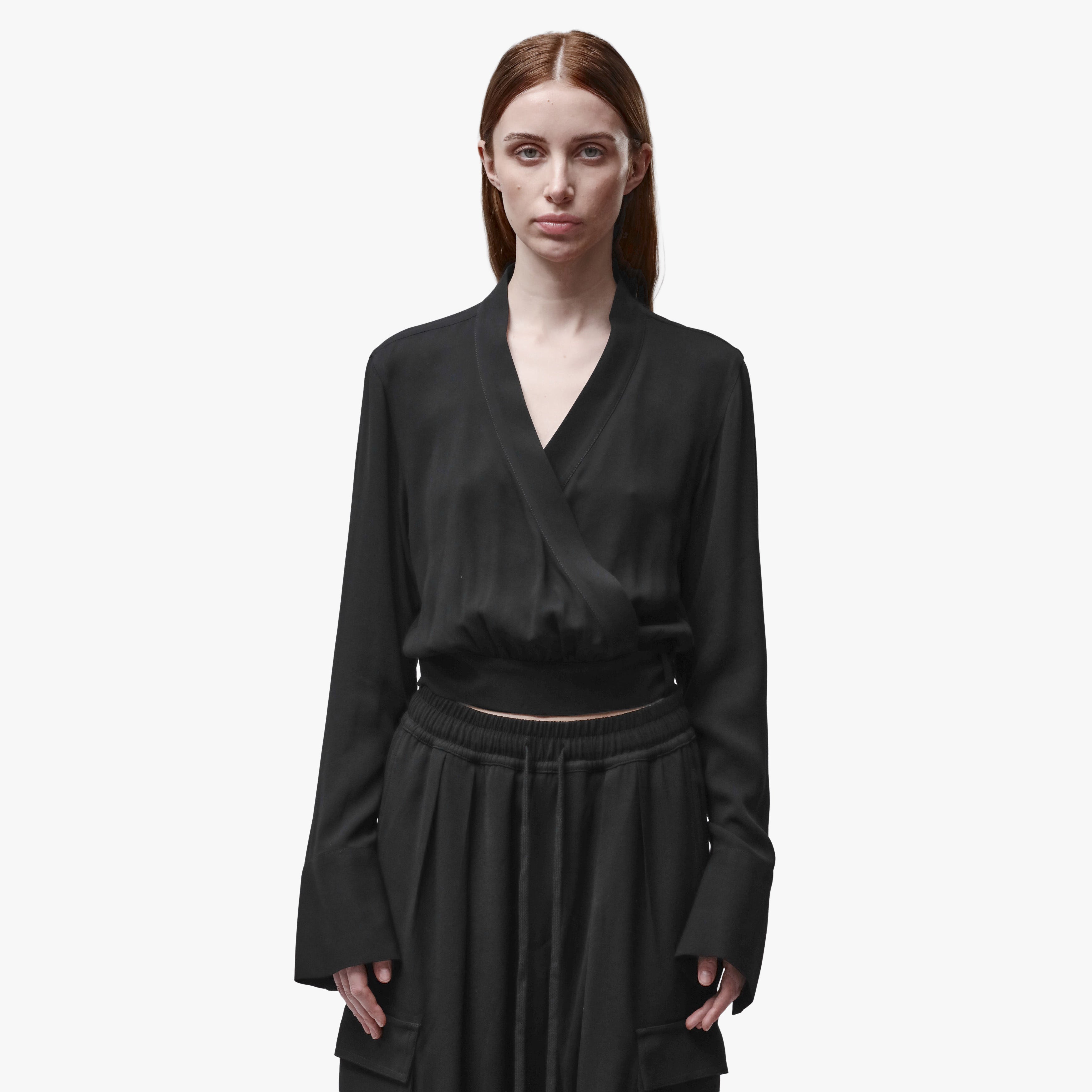 A woman wearing a black wrap top and black pants