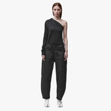 A woman wearing black barrel leg jeans and an asymmetrical top