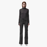 A woman wearing black flared jeans and a brown mock turtleneck shirt