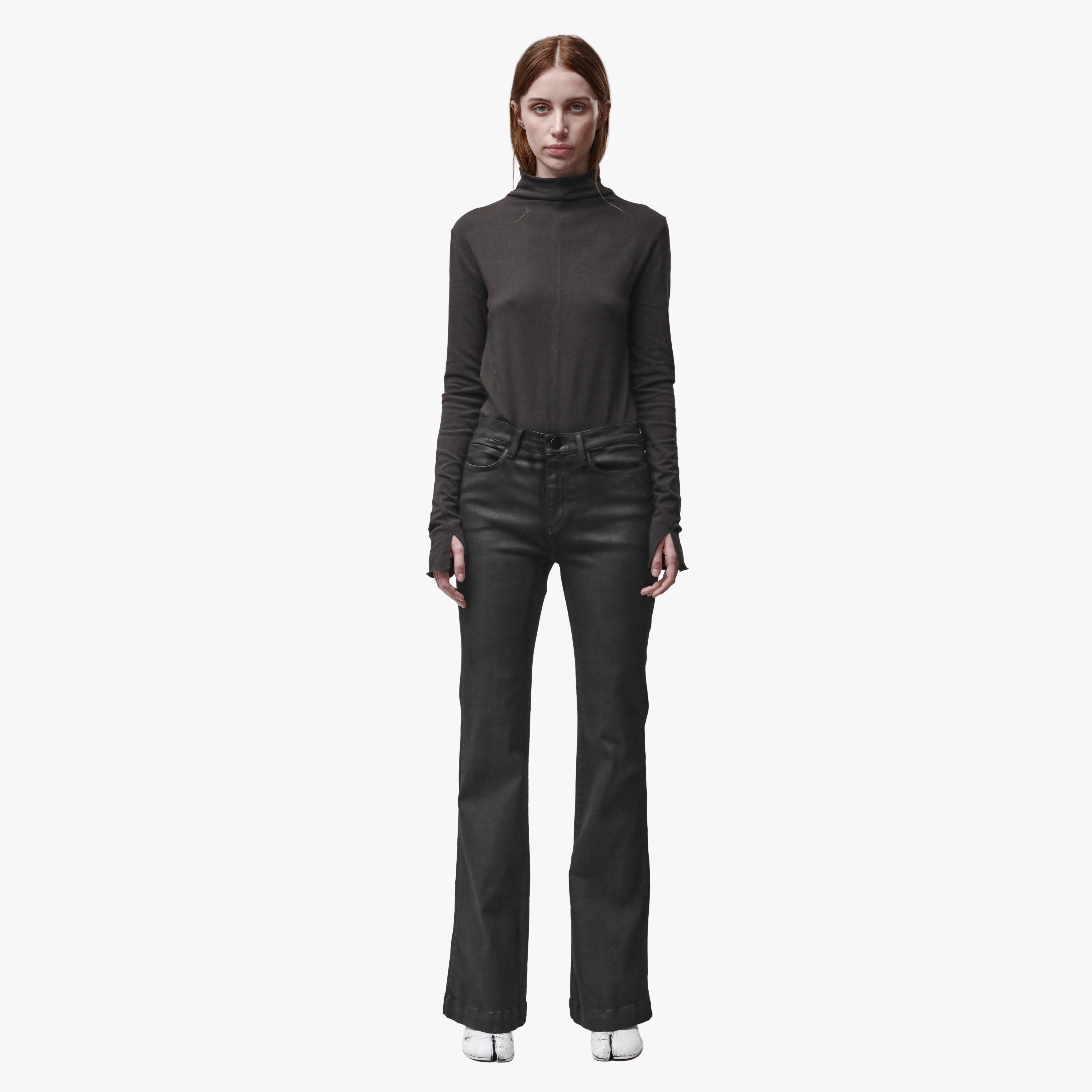 A woman wearing black flared jeans and a brown mock turtleneck shirt