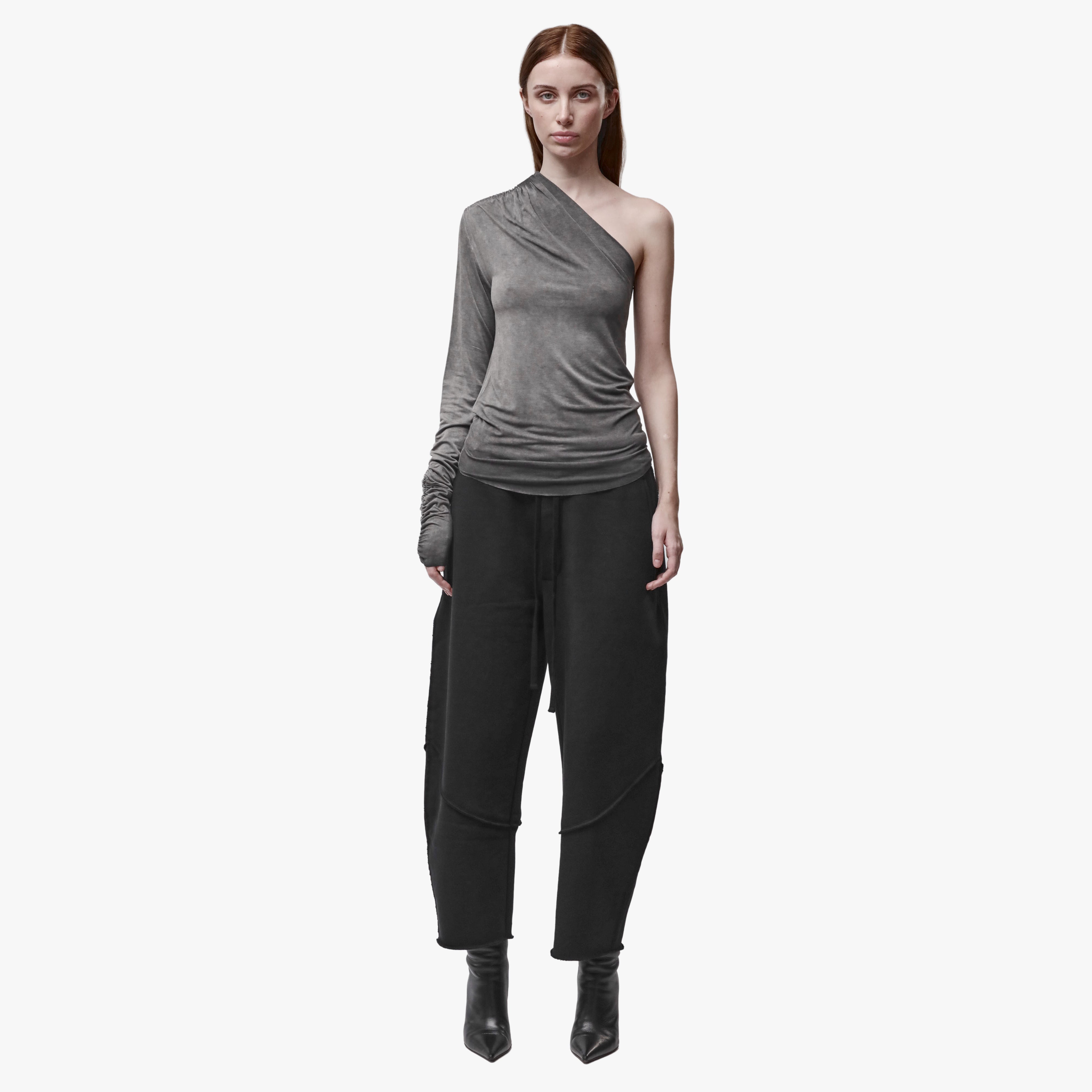 A woman wearing an asymmetrical grey top and black barrel pants
