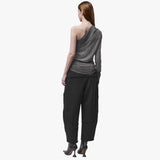 Back view of a woman wearing an asymmetrical grey top and black barrel pants