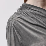 Shoulder detail of a woman wearing an asymmetrical grey top