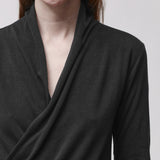 Neckline detail of a woman wearing a long sleeve black wrap top
