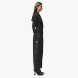 Profile view of a woman wearing a long sleeve black wrap top and black barrel jeans