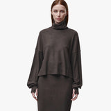 A woman wearing a brown turtleneck sweater