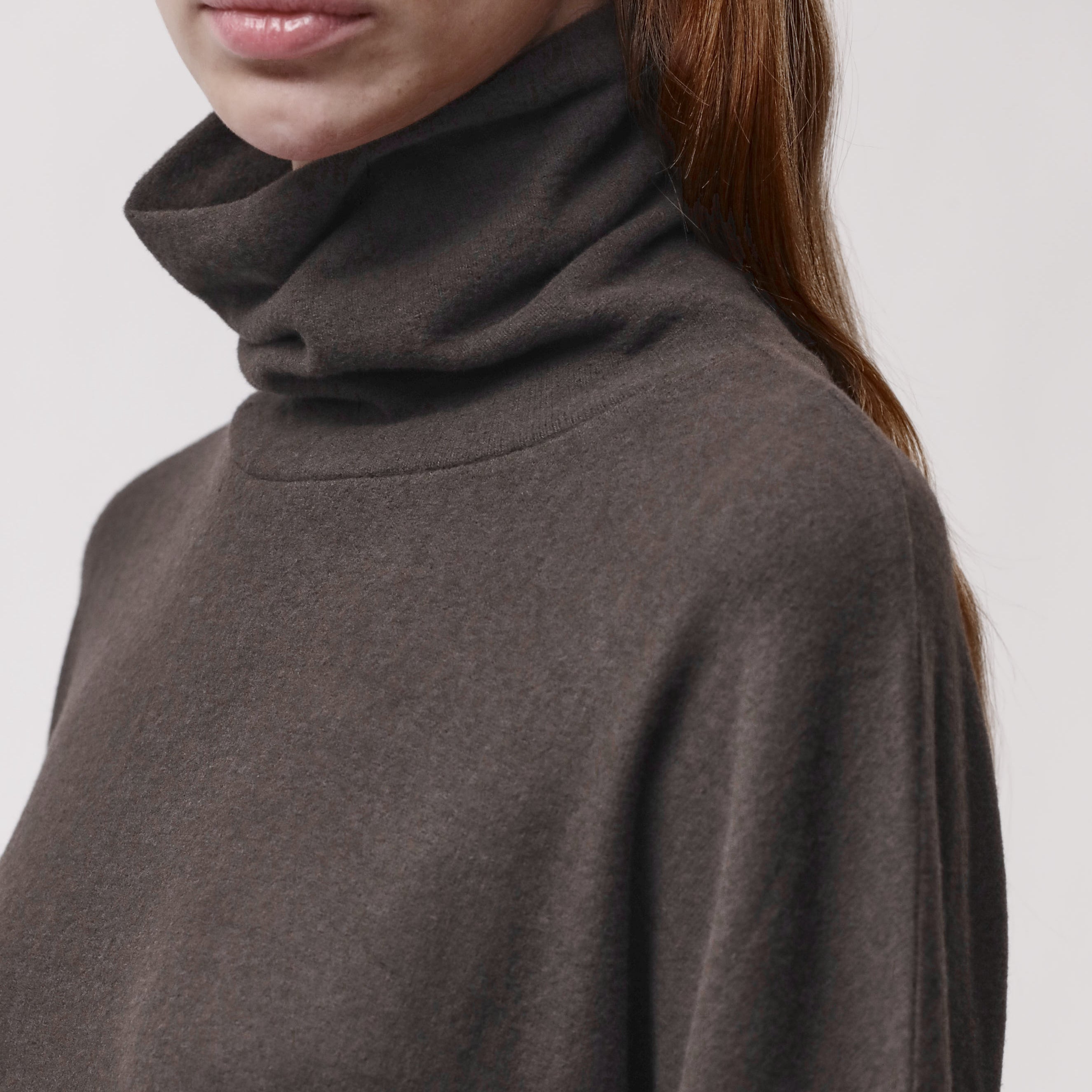 Neck detail of a woman wearing a brown turtleneck sweater
