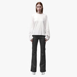 A woman wearing a relaxed white long sleeve crew neck t-shirt and black pants