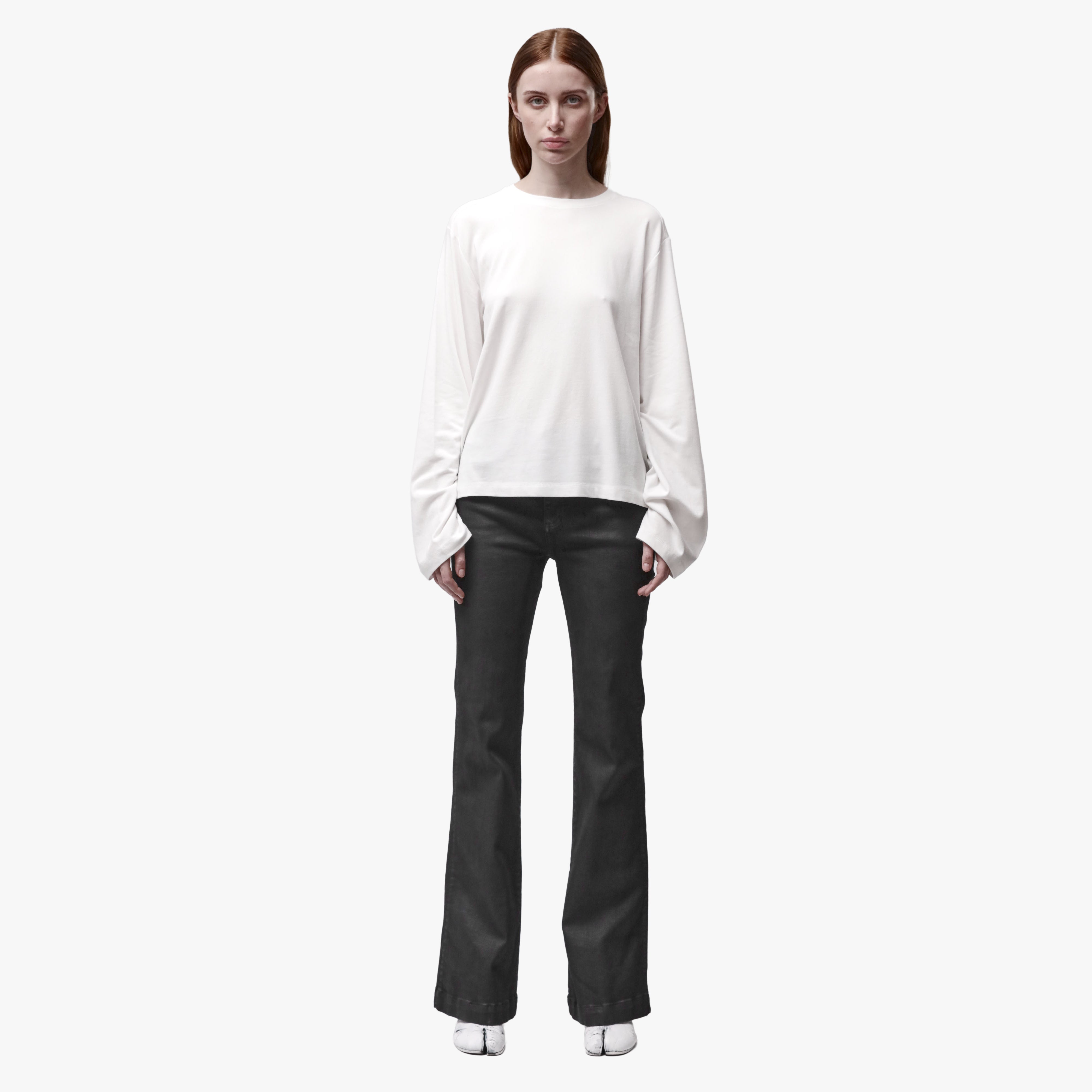 A woman wearing a relaxed white long sleeve crew neck t-shirt and black pants