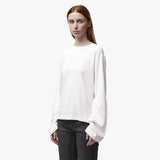3/4 angle of a woman wearing a relaxed white long sleeve crew neck t-shirt