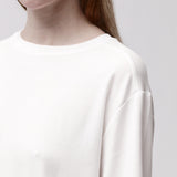 Shoulder detail of a woman wearing a relaxed white long sleeve crew neck t-shirt