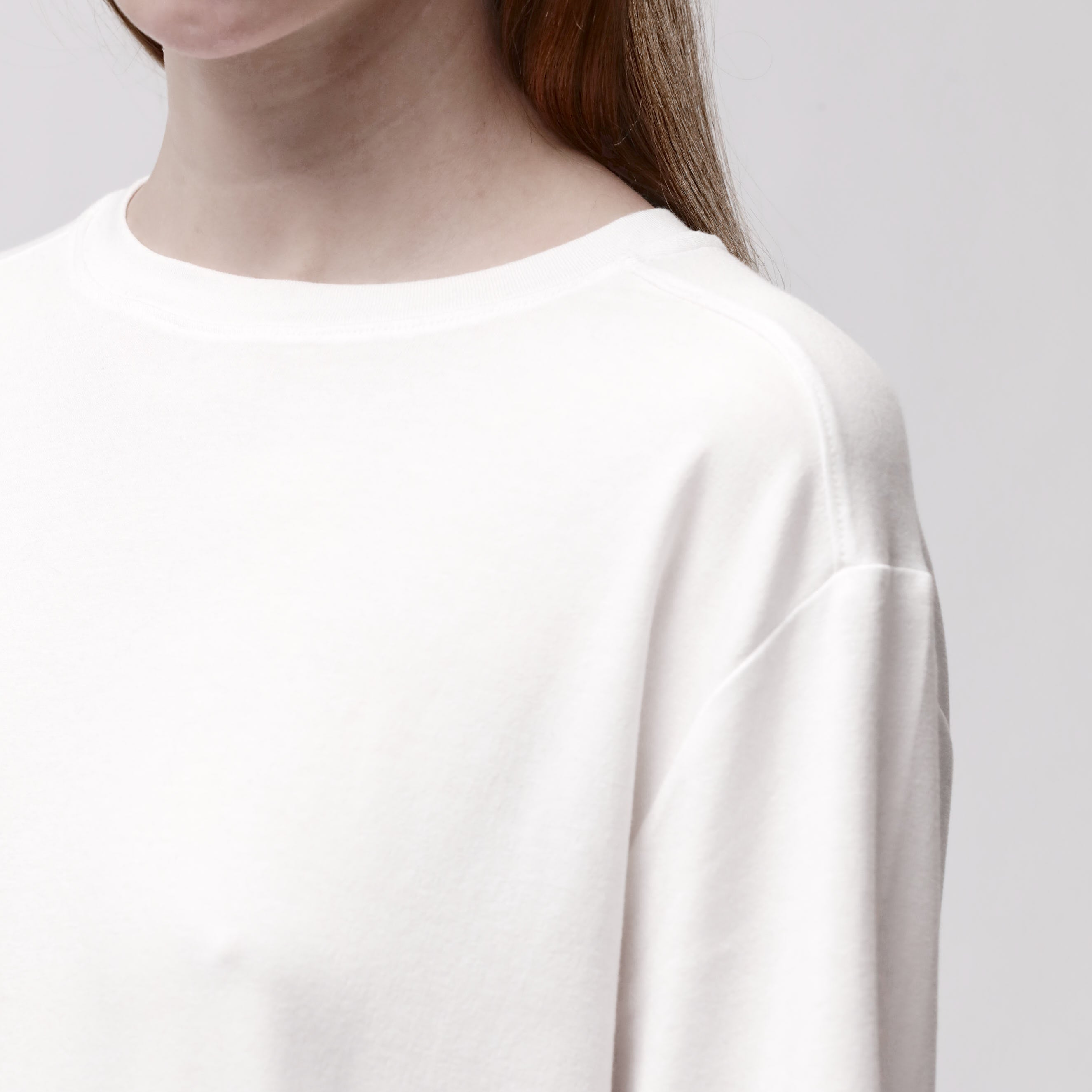 Shoulder detail of a woman wearing a relaxed white long sleeve crew neck t-shirt