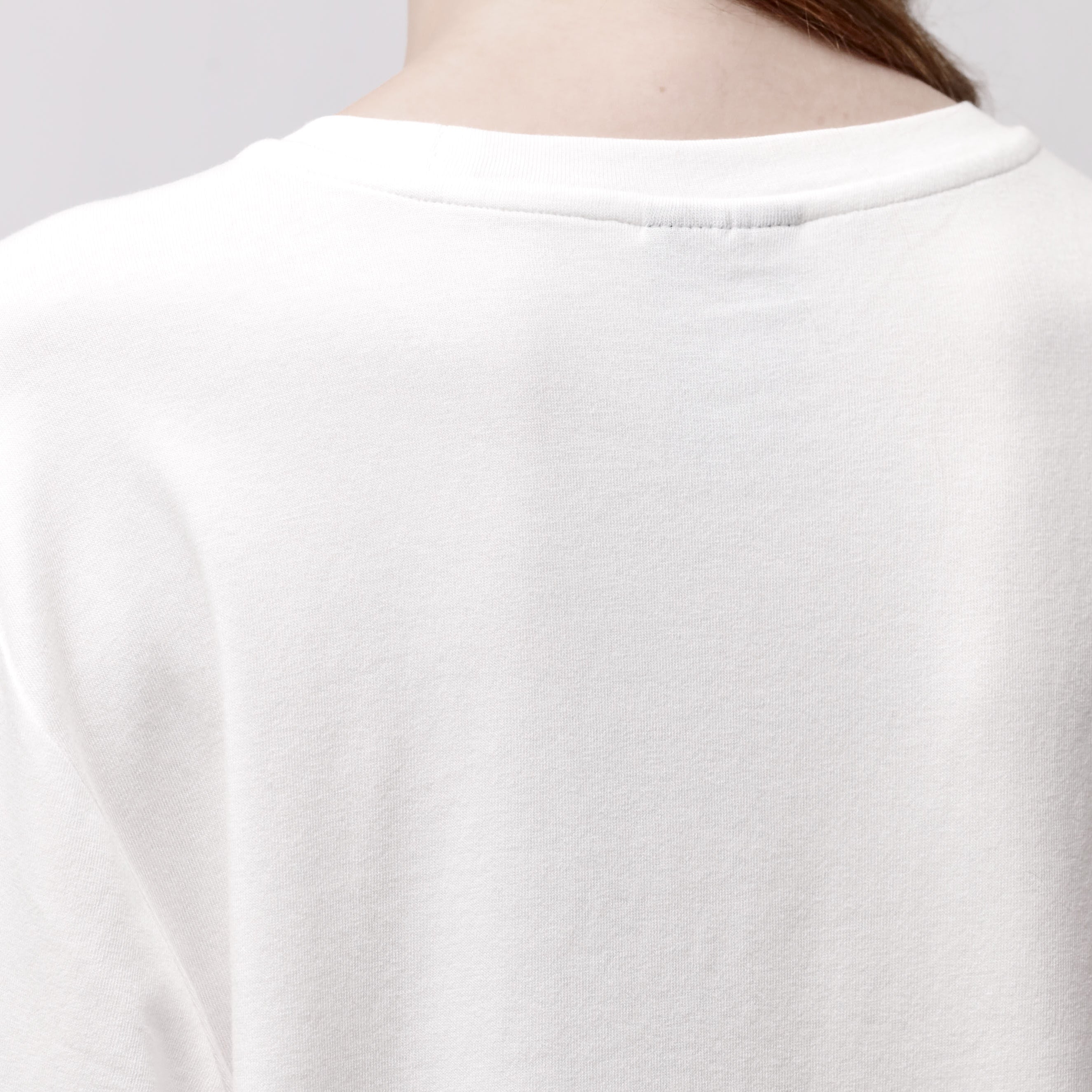 Back detail of a woman wearing a relaxed white long sleeve crew neck t-shirt