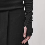 Sleeve detail of a woman wearing a long sleeve black t-shirt with a thumbhole
