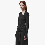 3/4 view of a woman wearing a long sleeve black t-shirt with a thumbhole and asymmetric neckline