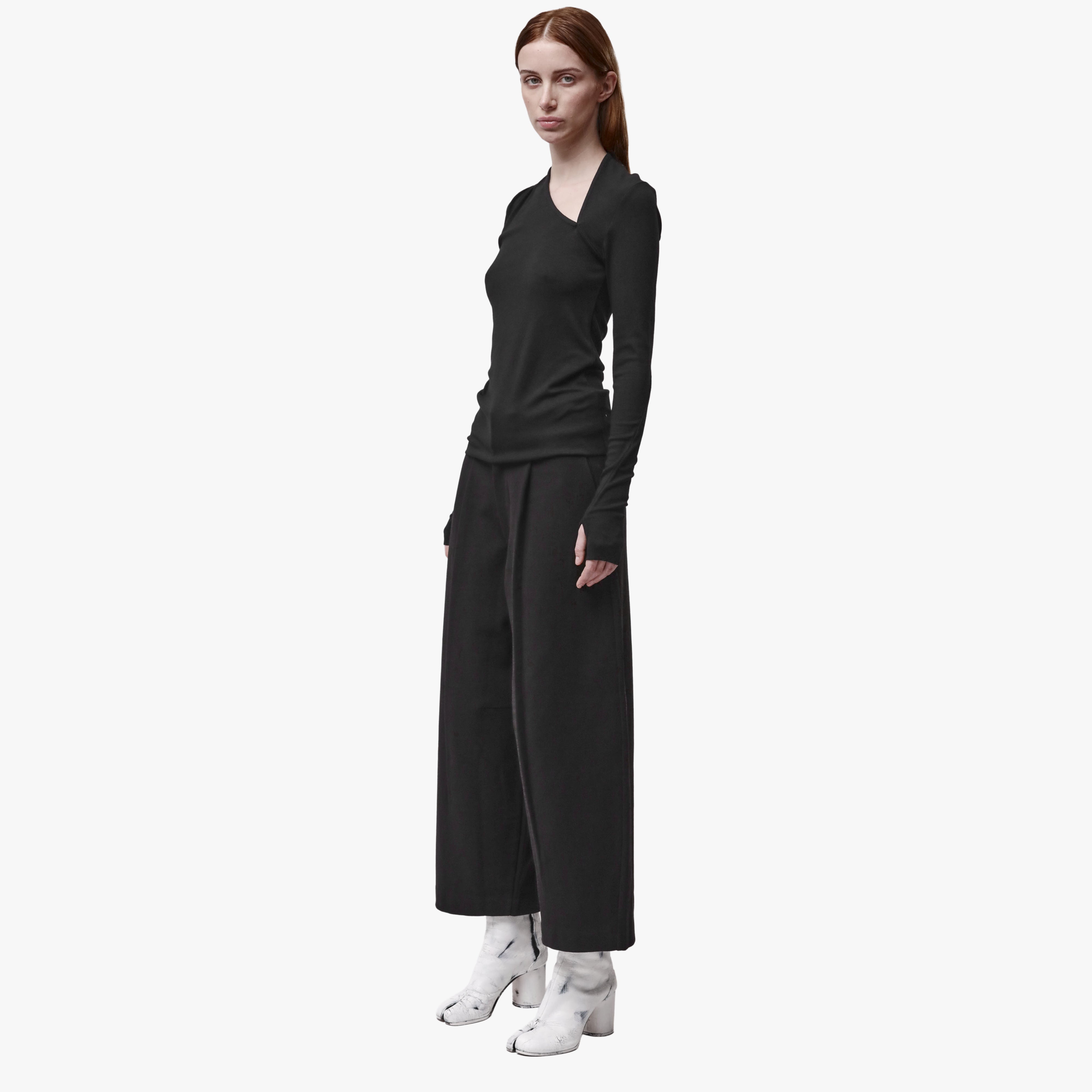 A woman wearing a black t-shirt with long sleeves, thumbholes and an asymmetric neckline